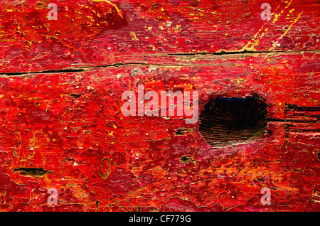 Grunge-Board roten Hintergrund gemalt. Nahaufnahme der alte Park Bench Kulisse. Stockfoto