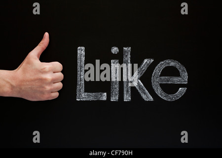 Thumbs up vor einer Tafel mit dem Wort wie mit weißer Kreide darauf geschrieben. Stockfoto