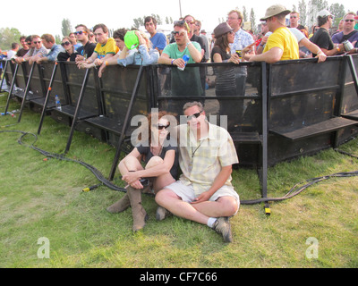 Zwei Menschen sitzen in VIP-Media-Bereich auf einem Musikfestival, durch Barrikade von Stehplatz Masse getrennt. Stockfoto