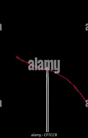 Nadel eingefädelt mit roter Baumwolle vor schwarzem Hintergrund Stockfoto