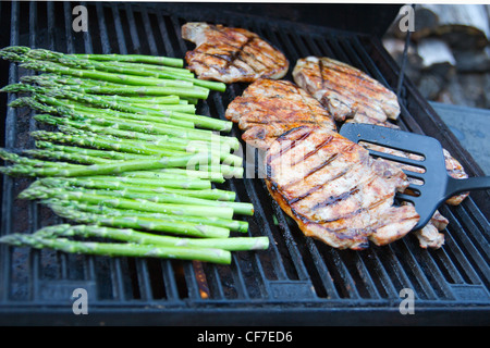 Schweinekoteletts und Spargelgrillen auf dem Grill im Freien. Stockfoto