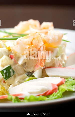 Salat mit Garnelen, Krebsfleisch, Gurken, Äpfel, Kartoffeln, Kopfsalat, Mais, Eiern und Mayonnaise Stockfoto