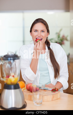 Porträt einer Frau, die eine Erdbeere essen Stockfoto