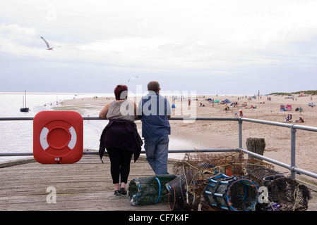 Paar-Entspannung am Ende der Pier, beobachten Familien spielen auf den breiten sandigen Strand unten Aberdovey, Wales, UK Stockfoto