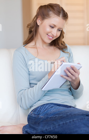 Lächelnde Frau Notizen auf ihrem sofa Stockfoto