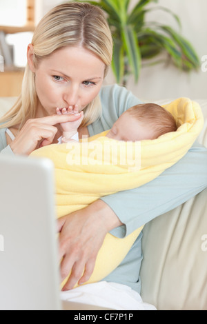 Mutter, küssen ihr Baby Hand beim Betrachten des Laptops Stockfoto