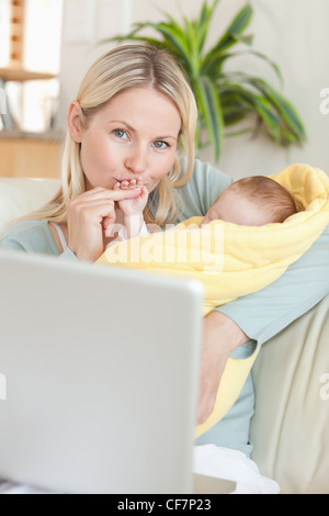 Mutter, küssen ihr Baby Hand beim Sitzen auf dem sofa Stockfoto