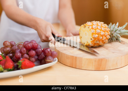 Nahaufnahme von weiblichen Händen eine Ananas schneiden Stockfoto