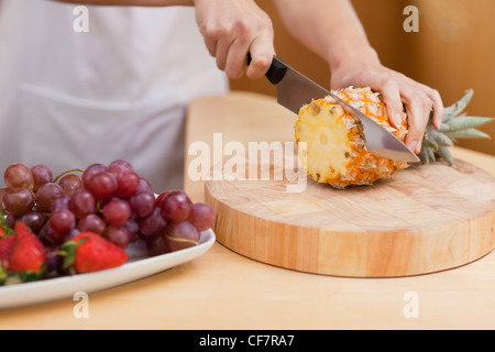 Nahaufnahme von jungen weiblichen Händen eine Ananas schneiden Stockfoto