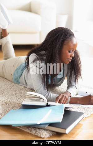 Frau liegend auf Teppich Hausaufgaben Stockfoto