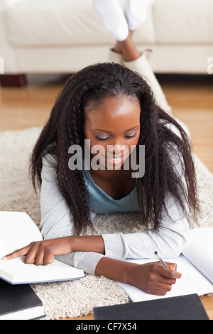 Frau liegend auf Teppich im Wohnzimmer Hausaufgaben Stockfoto