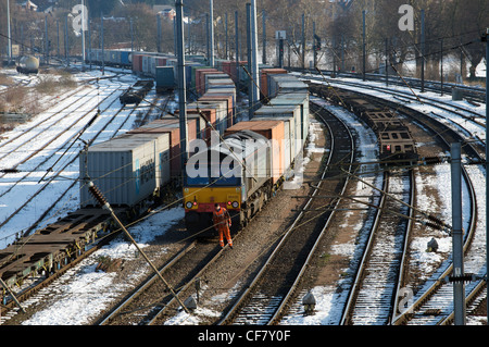 Eisenbahn-Ingenieur cheeking den Titel vor einem Güterzug auf ein Marshalling Yard, Ipswich, Suffolk, UK. Stockfoto