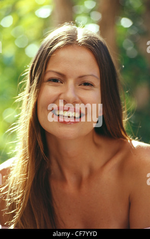 Brünette Frauen gerade Zentrum Abschied Haar, sitzen in einem Garten, tragen Lipgloss, lächelnd und Blick direkt in die Kamera, Stockfoto