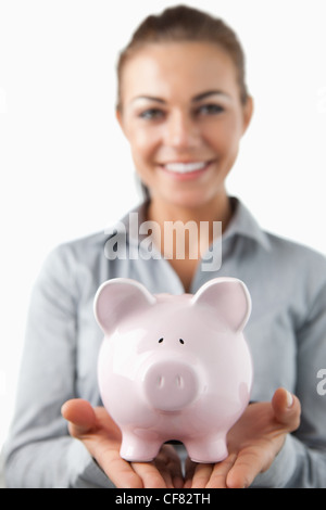 Nahaufnahme von Sparschwein statt mit einem Lächeln weibliche Bank Assistent Stockfoto