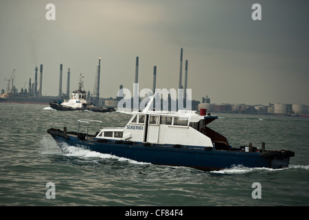 Kleine Boote passieren vor eine Offshore-Öl-Raffinerie in Singapur Stockfoto