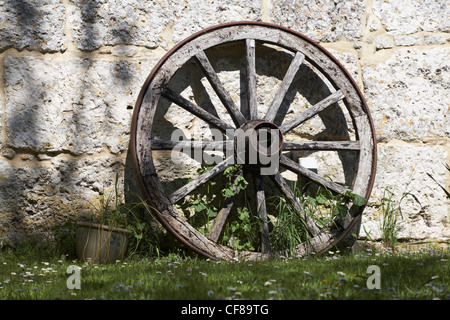 alte hölzerne Wagenrad Steinmauer gelehnt Stockfoto