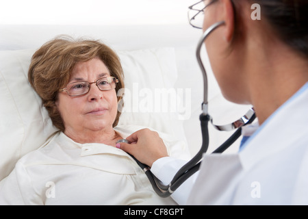 Arzt im Bett sitzend, Wiederherstellen von älteren Patienten untersucht Stockfoto