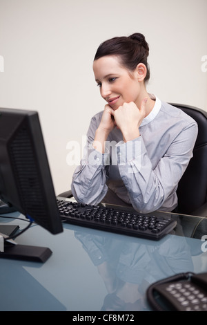 Glücklich lächelnd Geschäftsfrau sitzt an ihrem Schreibtisch Stockfoto
