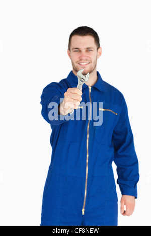 Schraubenschlüssel von lächelnden jungen Mechaniker im Blaumann gezeigt Stockfoto