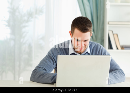 Mann arbeitet konzentriert in seinem Homeoffice auf seinem Notebook. Stockfoto