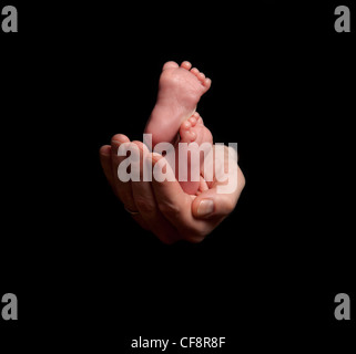 Des Babys Füße in die Hand seines Vaters gewiegt. Stockfoto