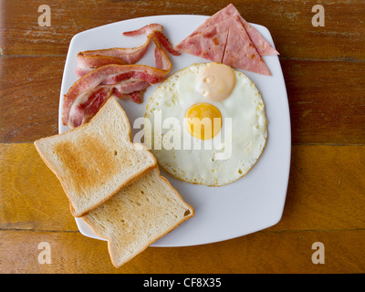 Rührei mit Speck und Toast auf weißen Teller auf den Tisch Stockfoto