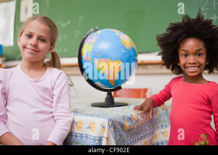 Schulmädchen posiert mit einem Globus Stockfoto