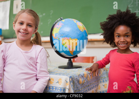 Niedliche Schulmädchen posiert mit einem Globus Stockfoto