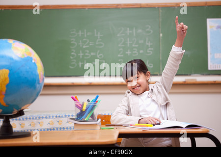 Schulmädchen hob ihre Hand auf eine Frage Antworten Stockfoto