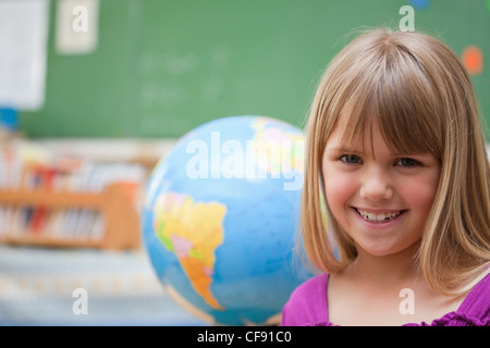 Schulmädchen posiert vor einem Globus Stockfoto