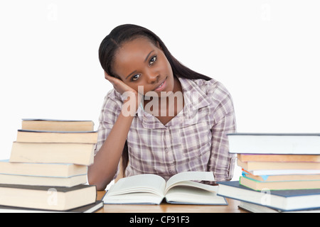 Junge Frau sitzt auf ihrem Schreibtisch mit Haufen Bücher Stockfoto