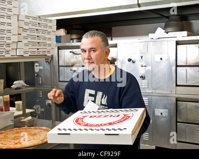 Pizza man mit verpackter Pizza vor dem Pizzaofen Stockfoto