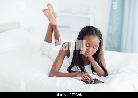 Frau mit einem Tabletcomputer auf ihrem Bett liegend Stockfoto