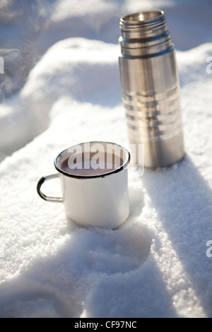 Becher und Thermoskanne mit heiße Schokolade an einem kalten Wintertag im Schnee Stockfoto