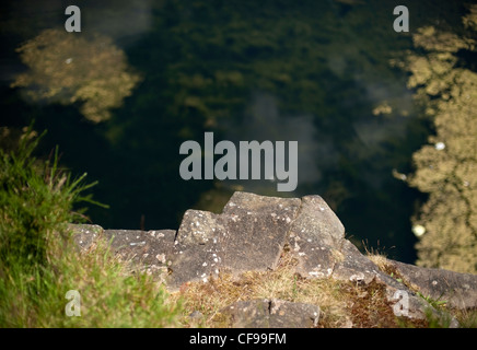 Der Blick auf die Kletterfelsen vom oberen Rand der Klippe, auf der Suche nach unten in das Loch im Auchinstarry Steinbruch, Schottland Stockfoto