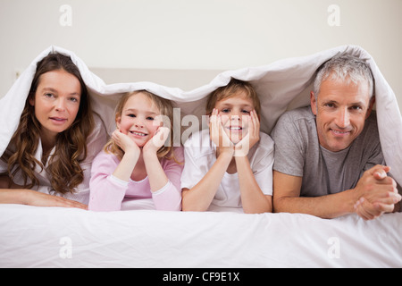 Familie unter einer Bettdecke liegen Stockfoto