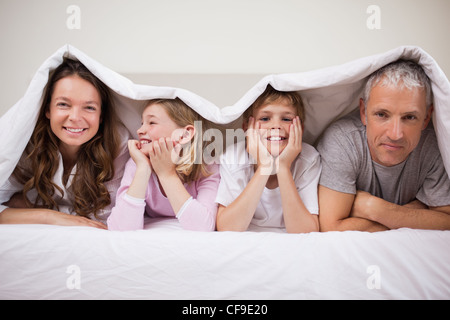 Glückliche Familie unter einer Bettdecke liegen Stockfoto