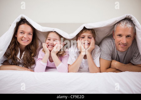 Spielerische Familie unter einer Bettdecke liegen Stockfoto