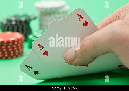 Aufstrebender zeigt Asse mit Poker-Chips in den Rücken auf grünem Hintergrund Stockfoto