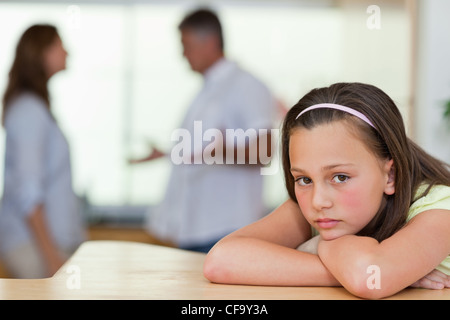 Trauriges Mädchen mit kämpfen Eltern hinter ihr Stockfoto