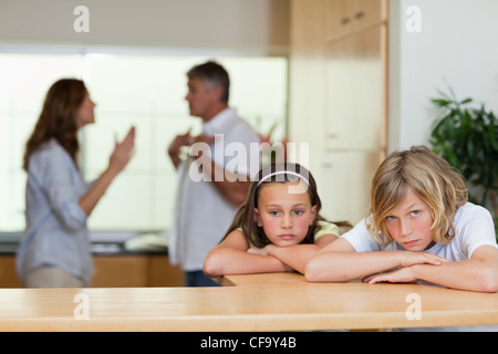 Sad sucht Geschwister mit streiten Eltern dahinter Stockfoto