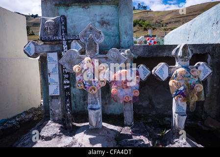 Künstliche Blumenkränze schmücken die Kreuze der Gräber auf dem kleinen Friedhof von der La Posada de Tigua in Ecuador. Stockfoto