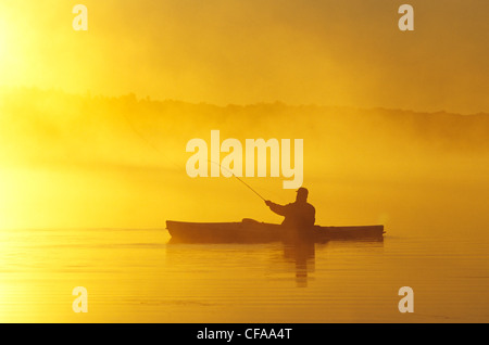 Mann mittleren Alters Fliegenfischen von Seekajak, Lake Muskoka, Ontario, Kanada. Stockfoto