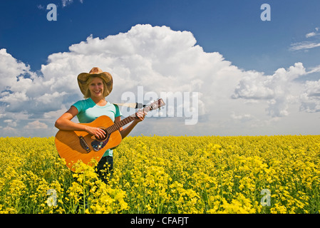 18 Jahre altes Mädchen mit Gitarre in einem Feld von Bloom Bühne Raps, Carey, Manitoba, Kanada Stockfoto