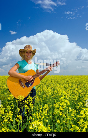 18 Jahre altes Mädchen mit Gitarre in einem Feld von Bloom Bühne Raps, Carey, Manitoba, Kanada Stockfoto