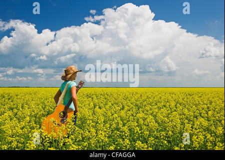 18 Jahre altes Mädchen mit Gitarre in einem Feld von Bloom Bühne Raps, Carey, Manitoba, Kanada Stockfoto