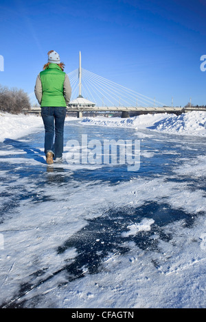 Frau der gefrorenen Red River vor der Esplanade Riel Brücke spazieren. Die Gabeln, Winnipeg, Manitoba, Kanada. Stockfoto