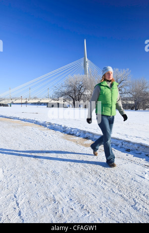 Bewegung verschwommenes Bild der Frau zu Fuß im Winter. Esplanade Riel Brücke im Hintergrund. Die Gabeln, Winnipeg, Manitoba, Kanada. Stockfoto