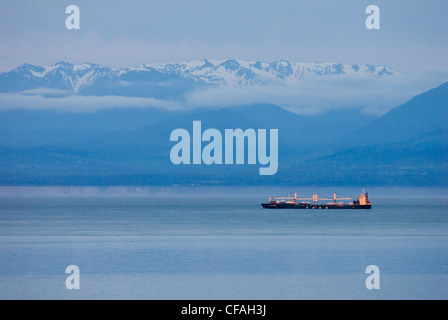 Ein Frachter durchläuft Starit Juan de Fuca mit den Olympic Mountains im Hintergrund, British Columbia, Kanada. Stockfoto
