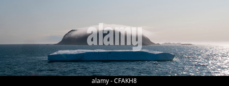 Eisberg vorbei einer nebligen Monumental-Insel in der Davis-Straße vor der Küste von Baffin Island, Nunavut, Kanada. Stockfoto